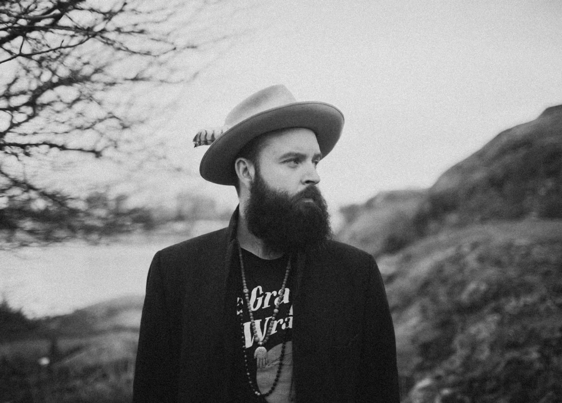 Black and white photo of person in hat and jacket outdoors.