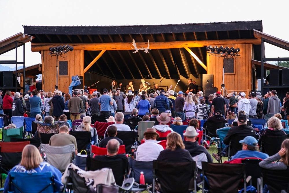 A crowd sitting in lawn chairs gathered around a bandstand watching the performers