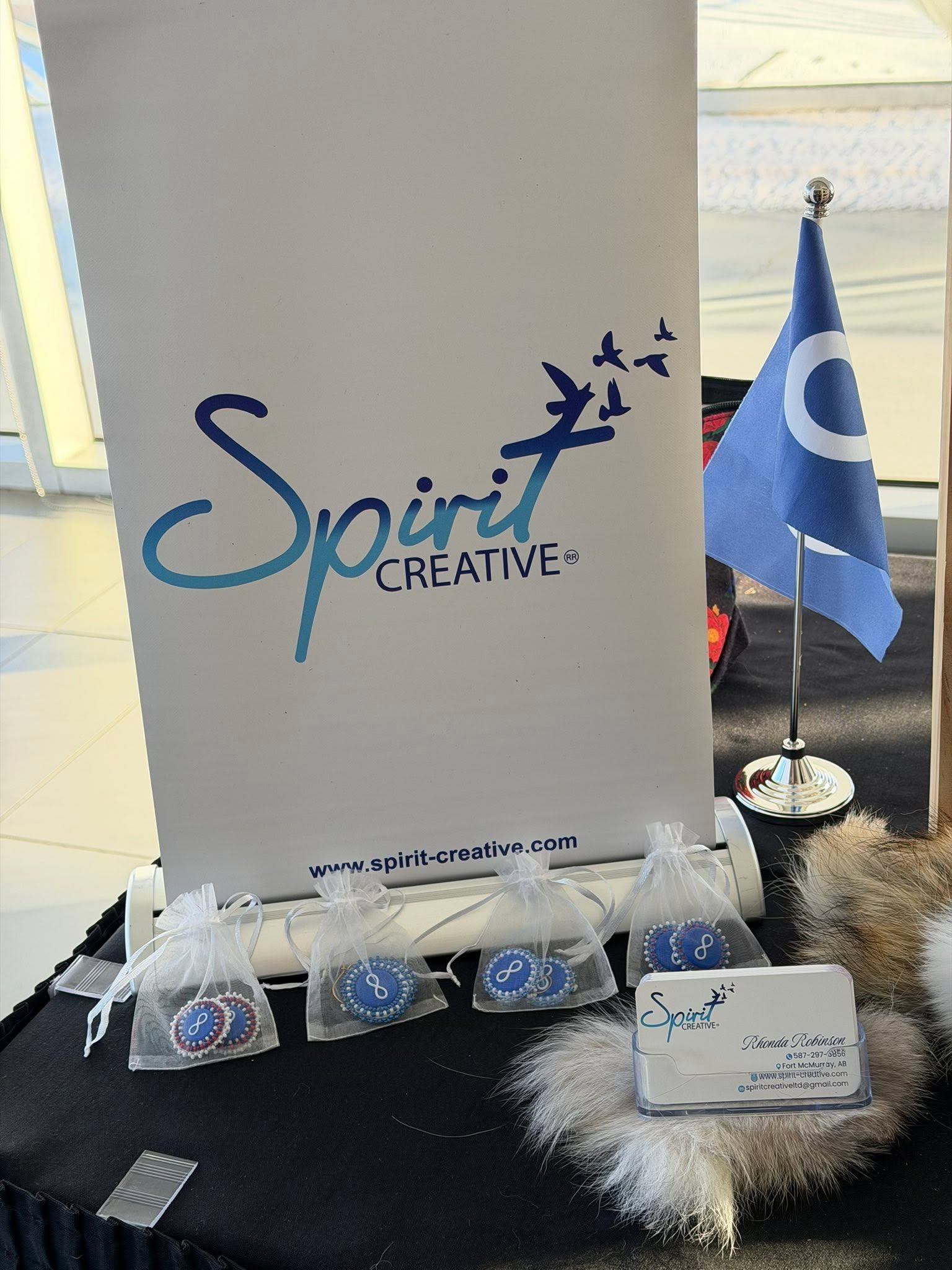 Spirit Creative display with banner, small blue flag, gift bags and business cards.