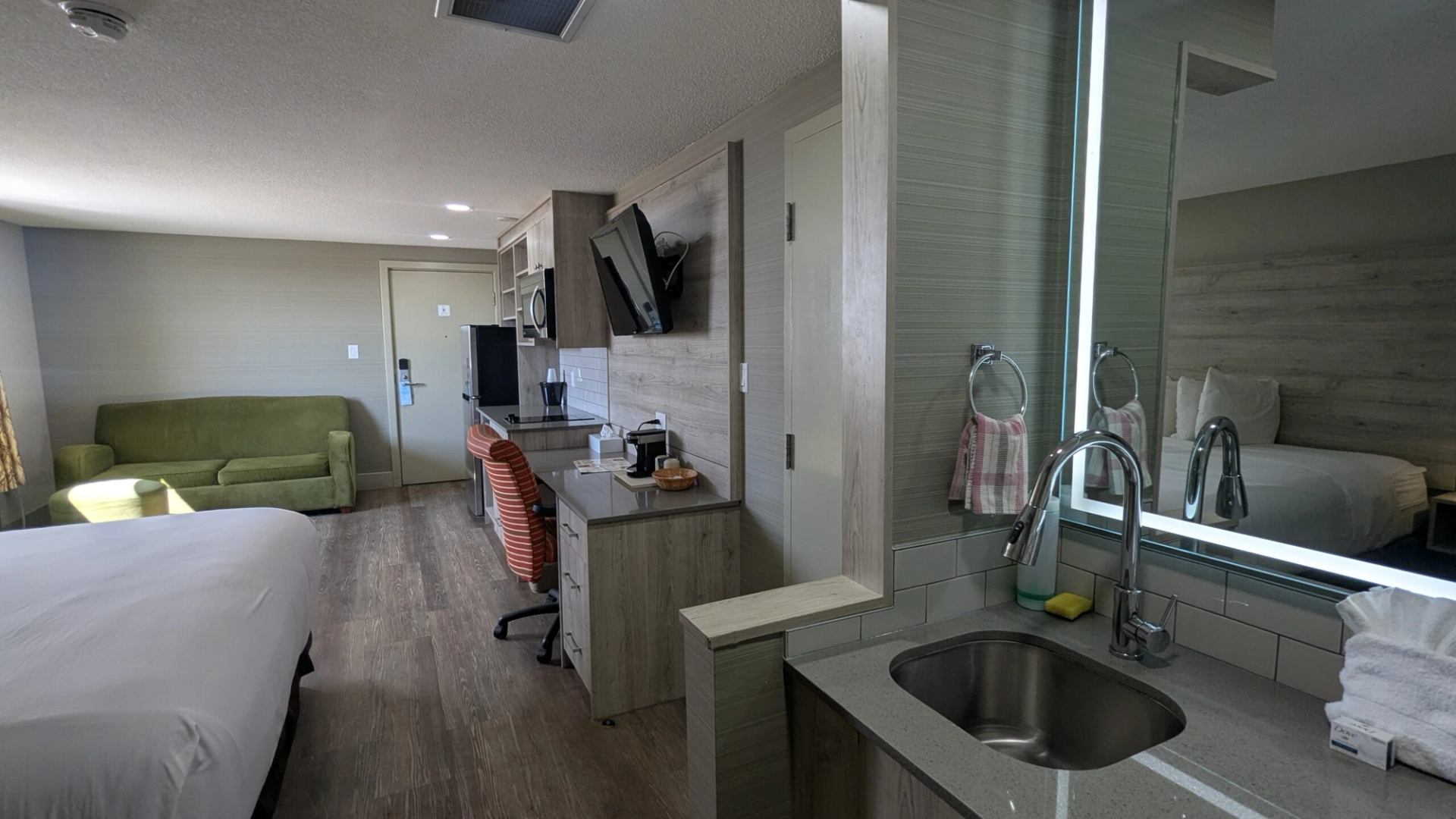 Hotel room with bed, sofa, desk, and kitchenette at Imperial Inn.