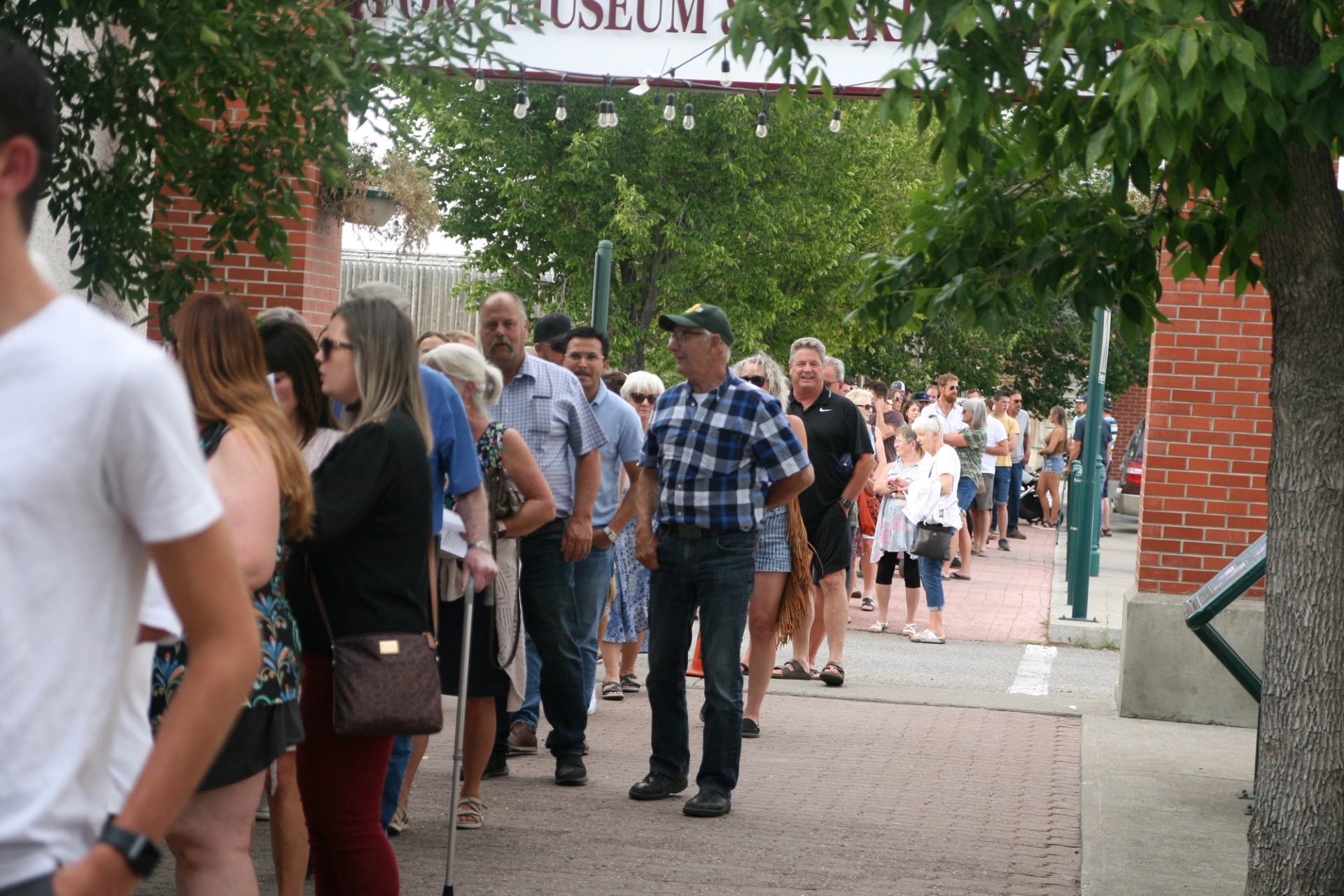 People stand in a long line outside a museum building.