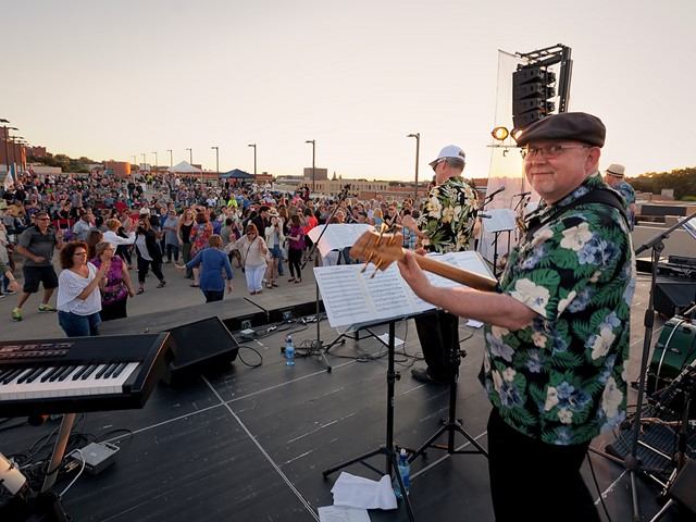 Band performs outdoors at Medicine Hat JazzFest with a large crowd in the background.