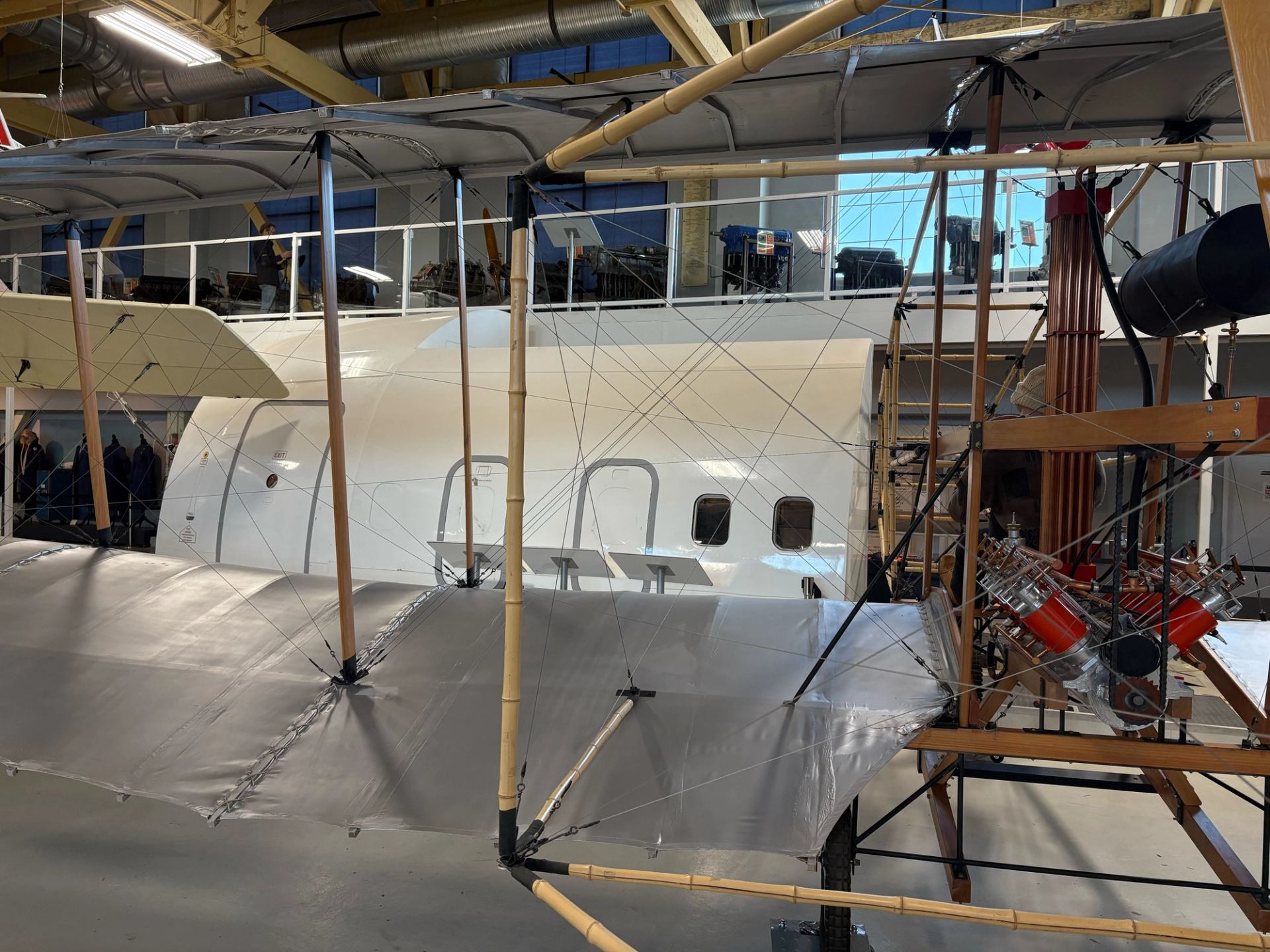 Historic early aircraft inside an aviation museum, showing fabric wings, wood framing, and engines.