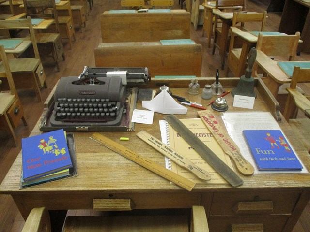Typewriter, quills, and ink bottles on display tables inside Onoway Museum.