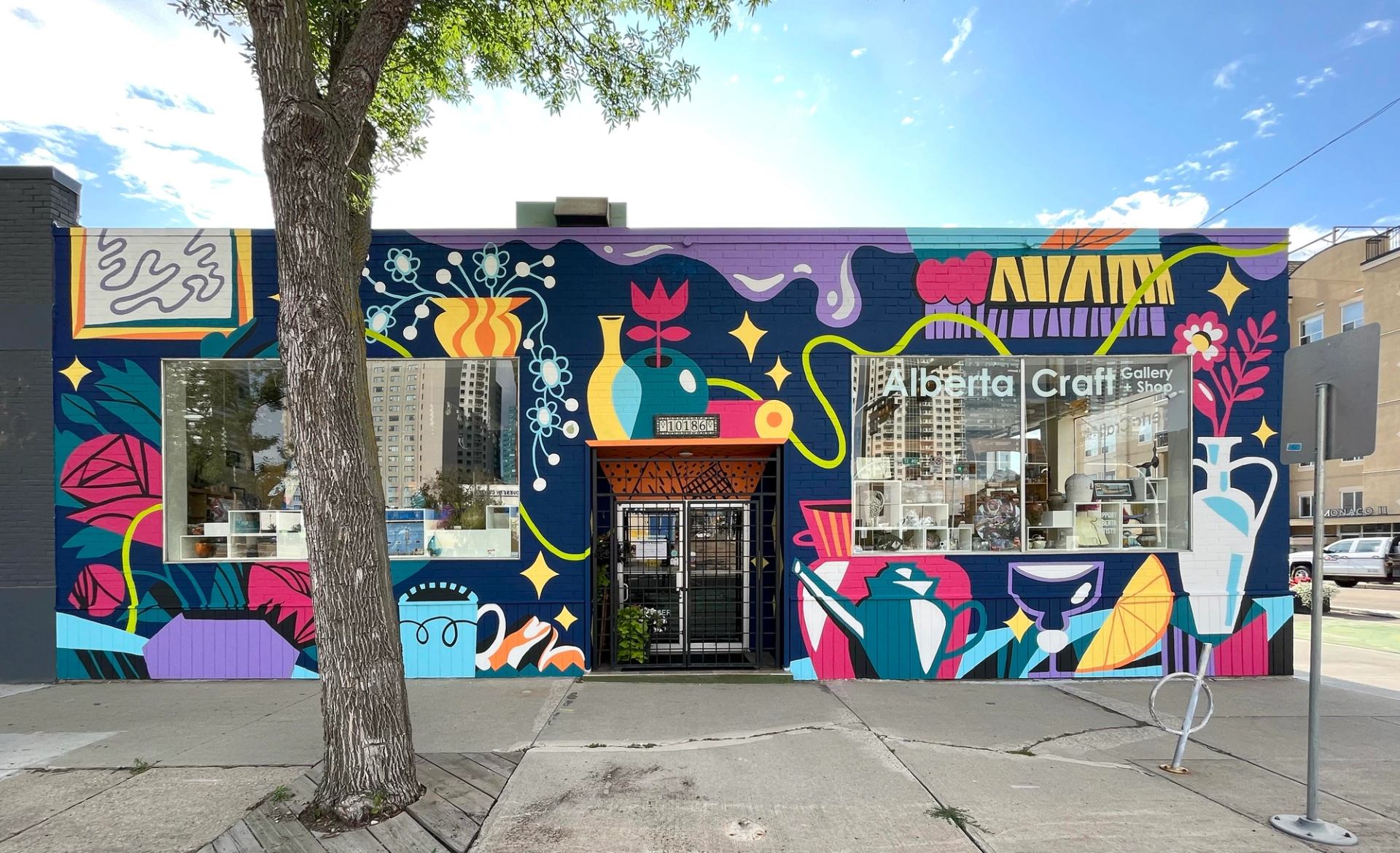 Colourful Alberta Craft storefront mural with abstract plants, vases and geometric shapes on brick.