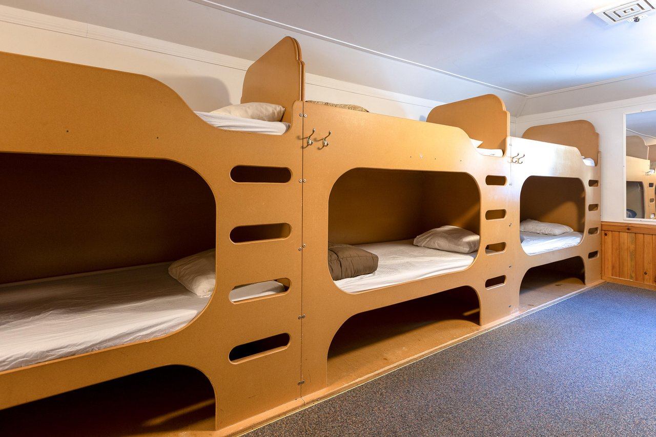 Shared bunk room with wooden beds, carpeted floor, and warm lighting.