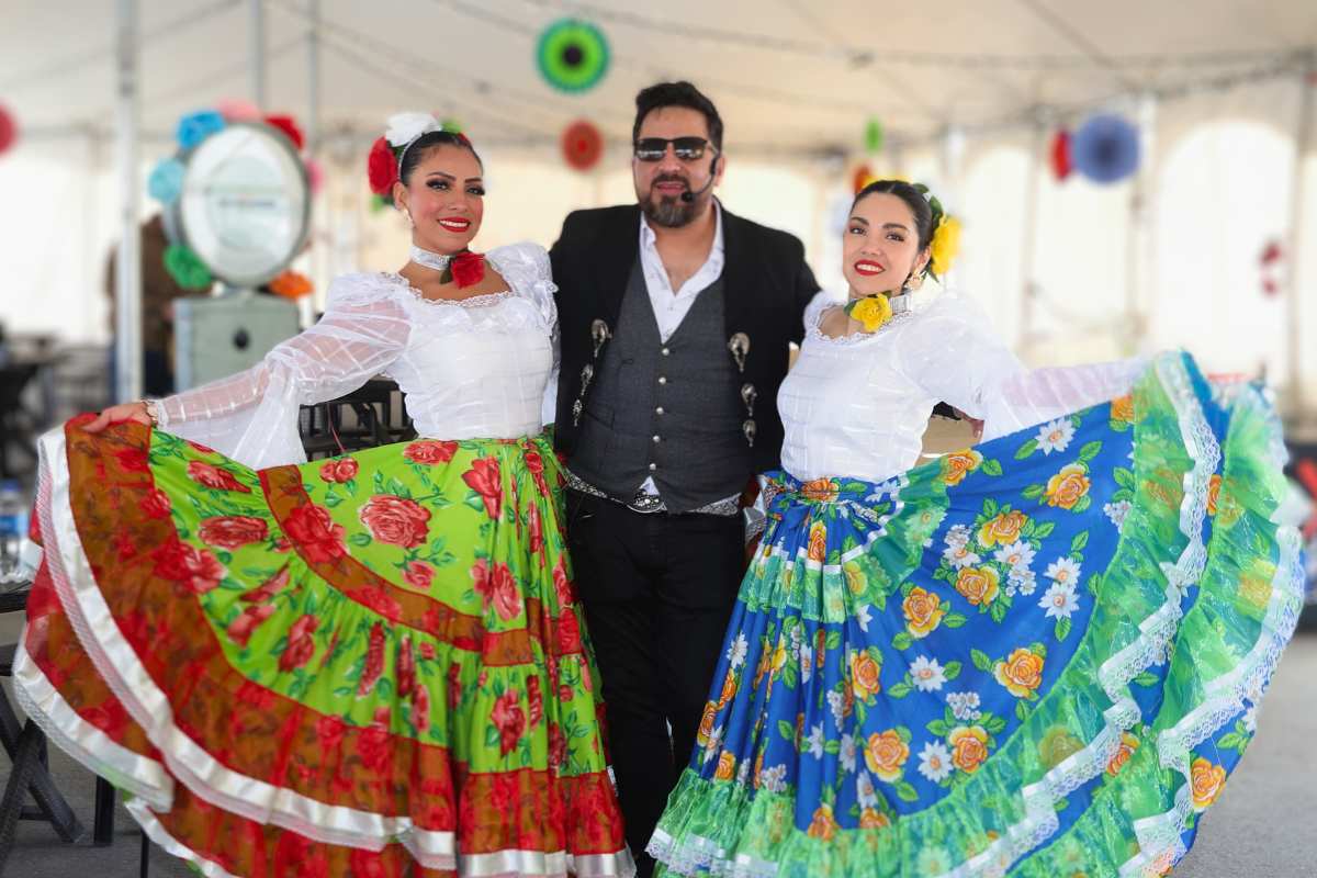 A man standing between two women dressed in their festive wear.