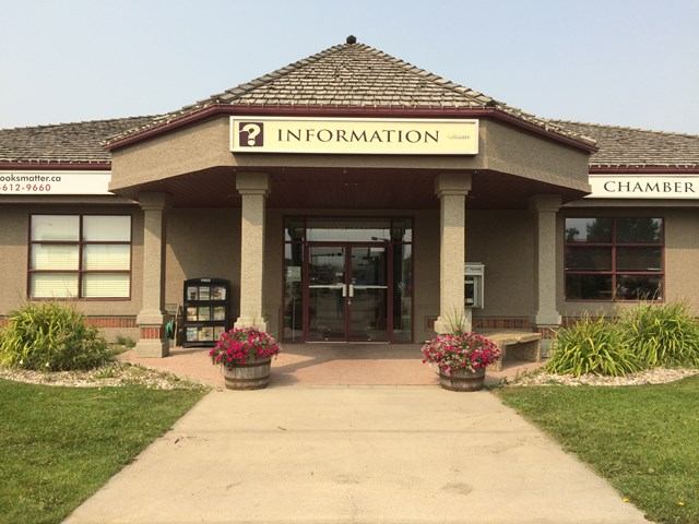 Info center with entrance sign, flower pots, and a path leading to the door.