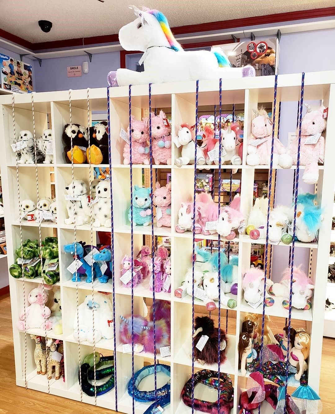Toy store display with hanging stuffed animals on blue-and-white beaded strings.