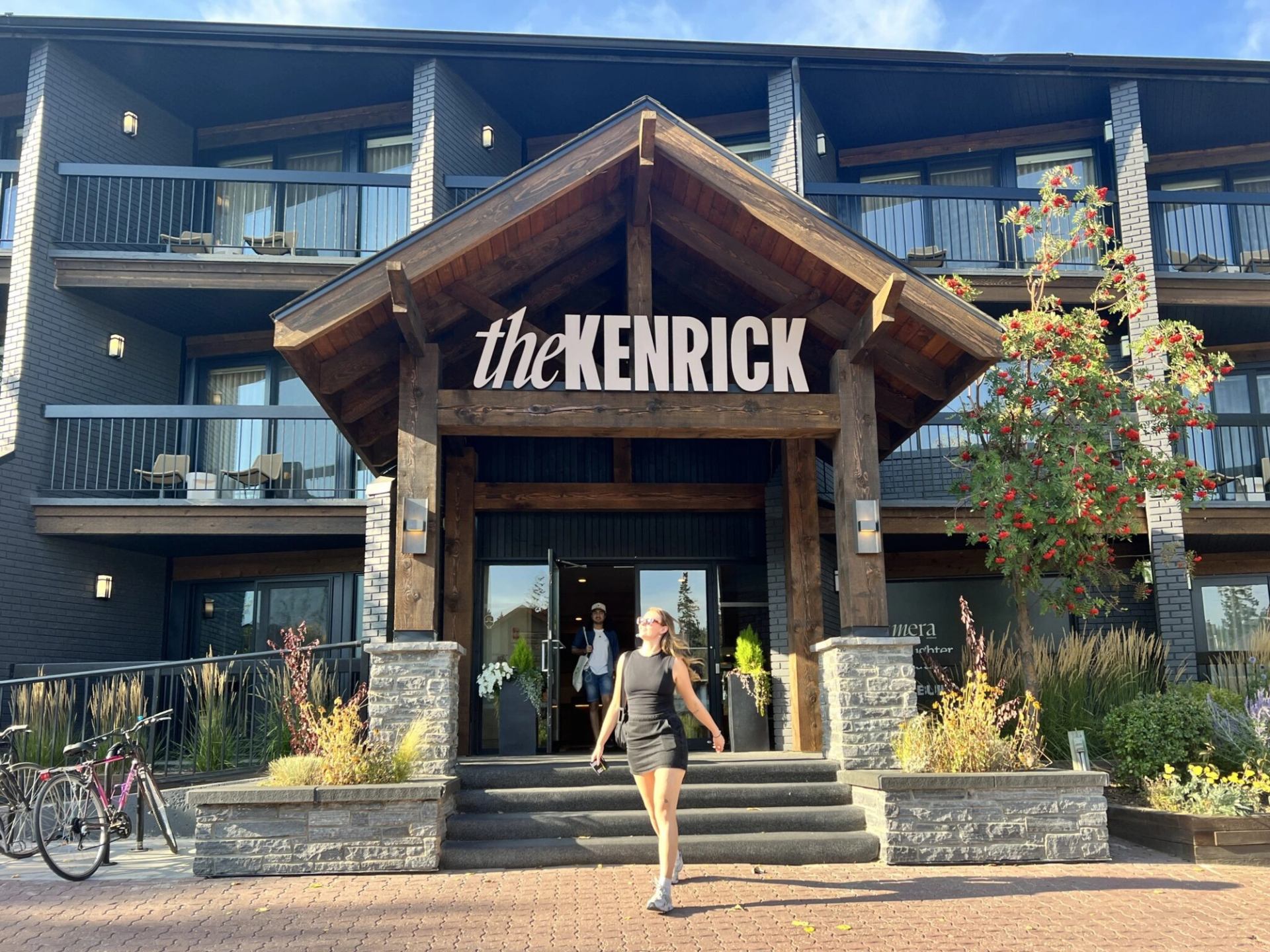 Rustic hotel entrance with wood beams, stone pillars, and balconies.