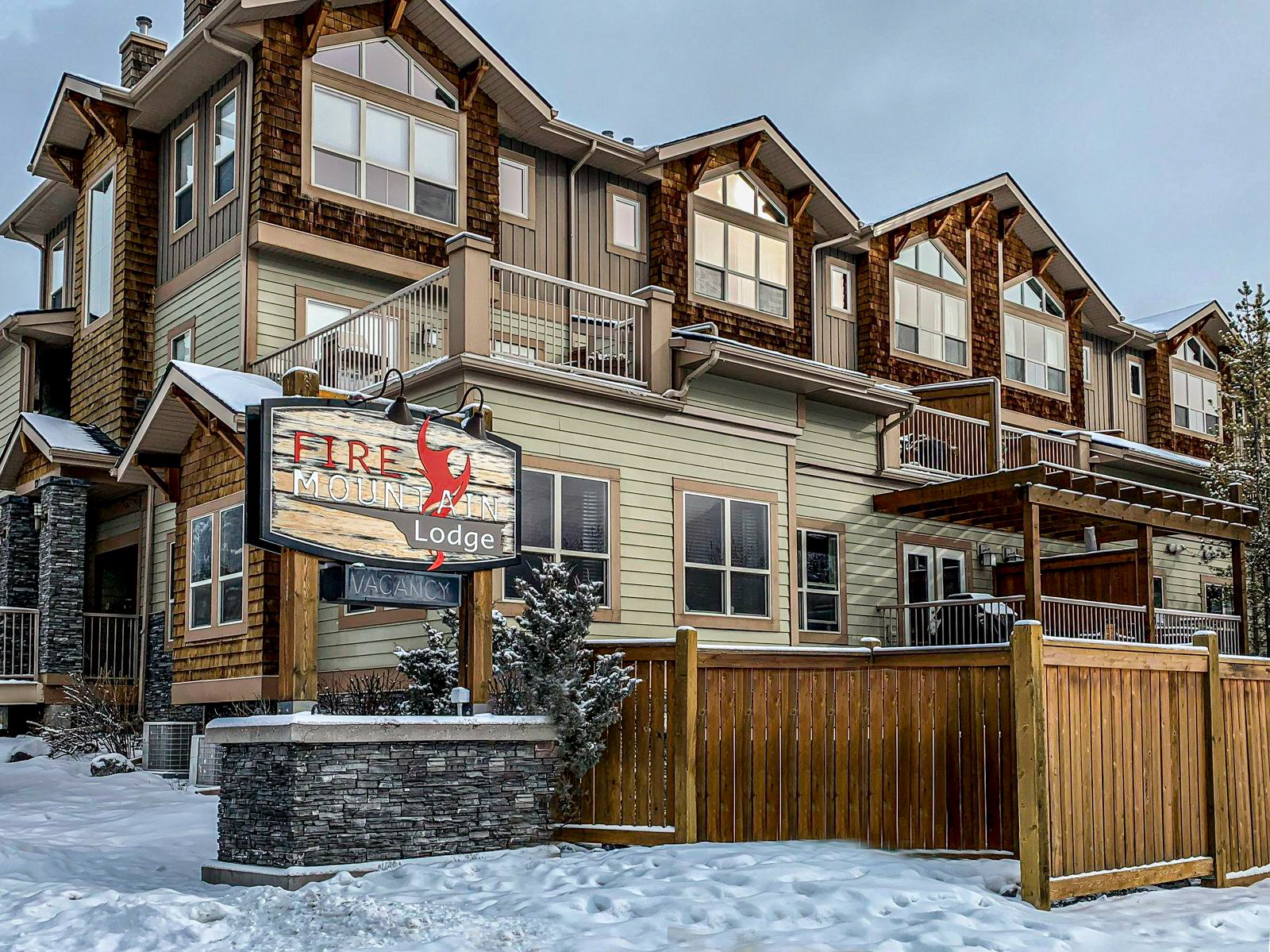 Fire Mountain Lodge exterior with balconies, wooden fencing and snow-covered grounds.