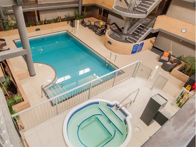 Indoor hotel pool area with large swimming pool and adjacent hot tub.