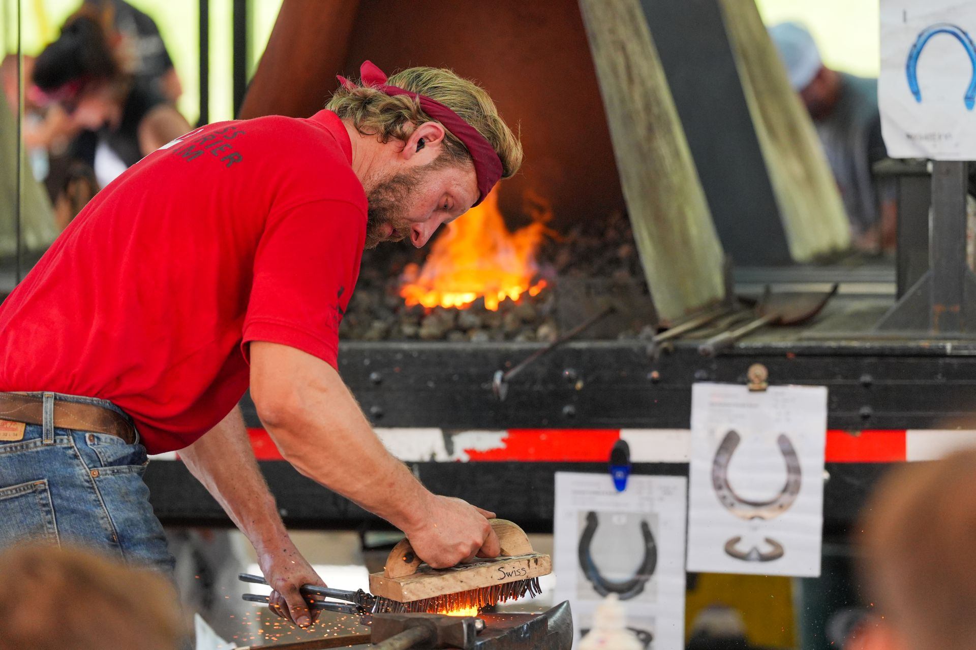 Blacksmith working on a horseshoe by the forge.