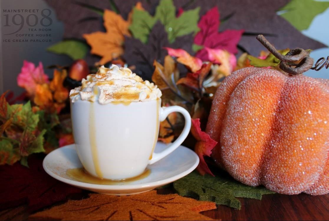 Pumpkin spice latte topped with whipped cream and caramel, surrounded by fall leaves