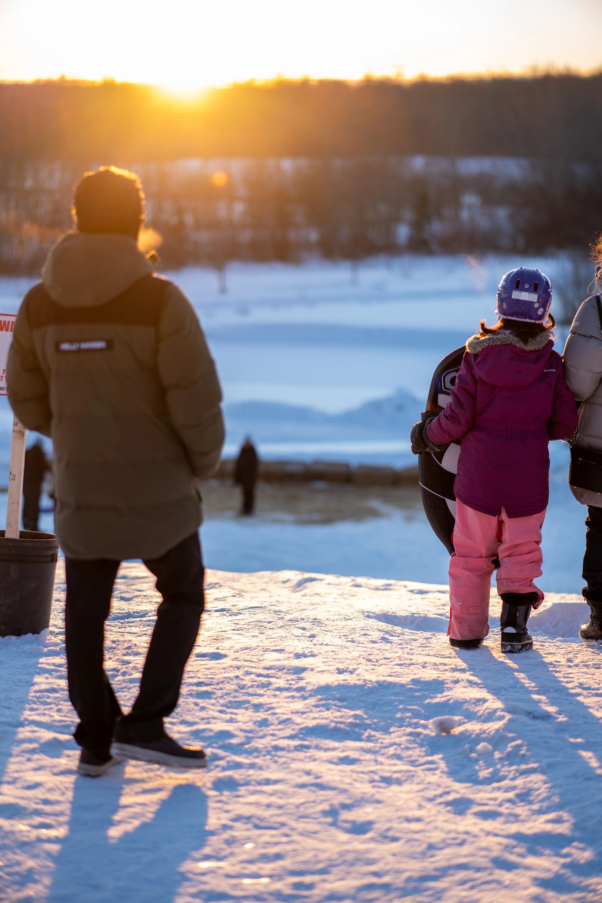 People standing on snowy ground at sunset during Winter Wonderland Festival.