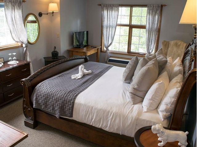 Cozy bedroom with wood furniture, soft lighting, and towel art on the bed.