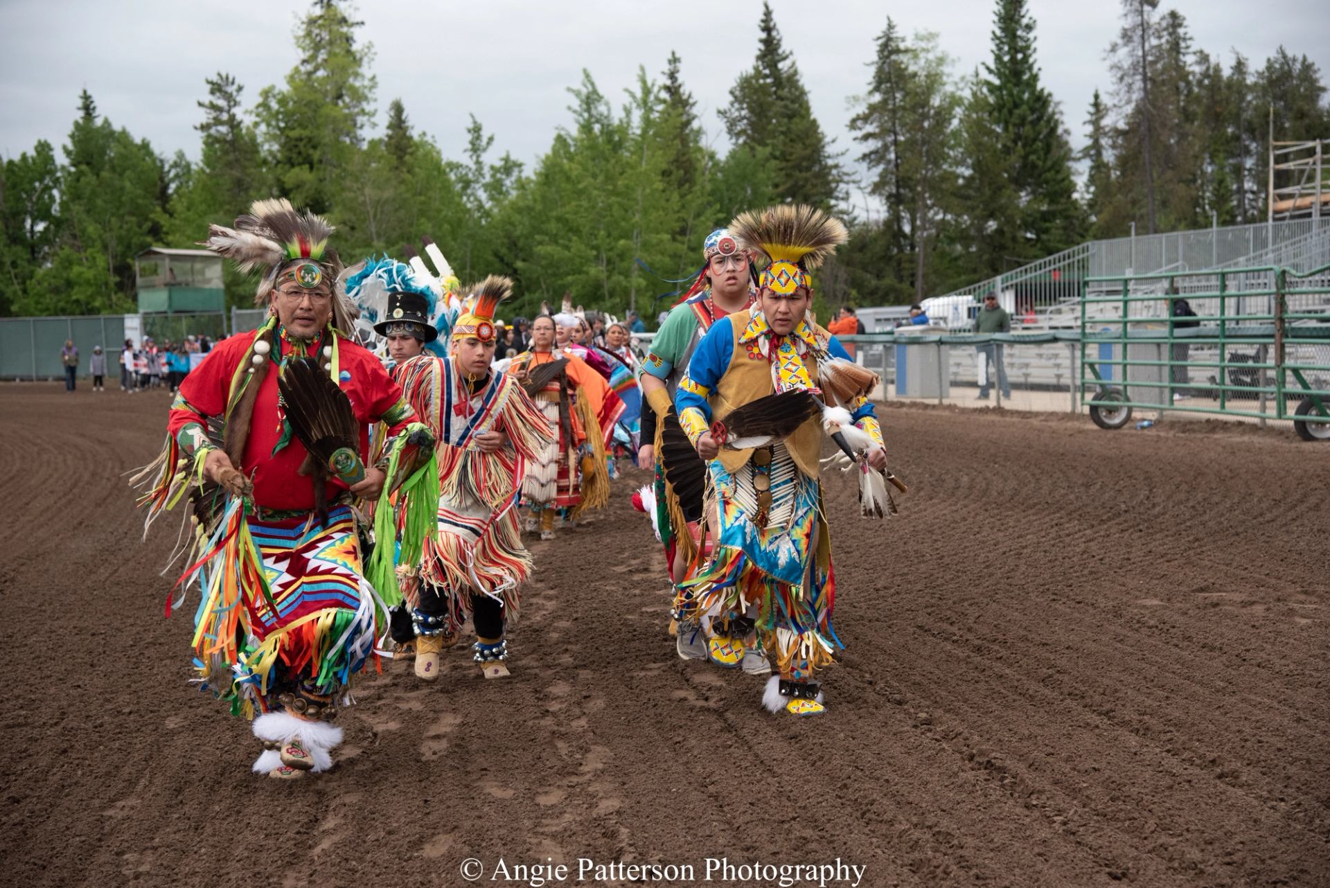 Group of performers in colorful regalia walking together in the arena.