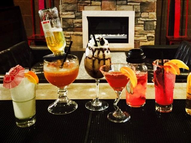 Colorful cocktails by a fireplace at Our Flames Restaurant & Lounge.