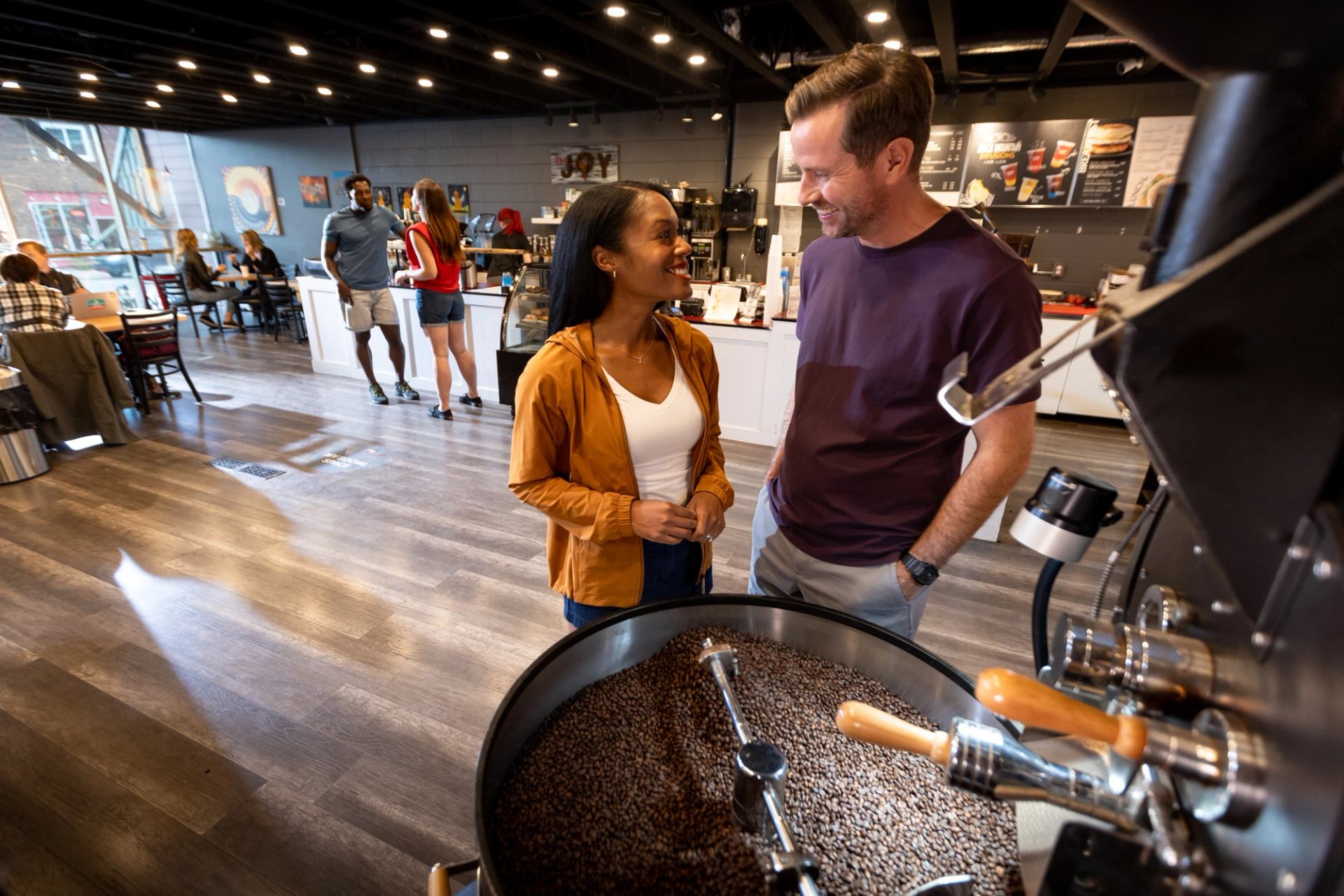 Couple watching coffee roasting, another couple in background.