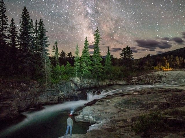 A hiker looks up at the night sky.