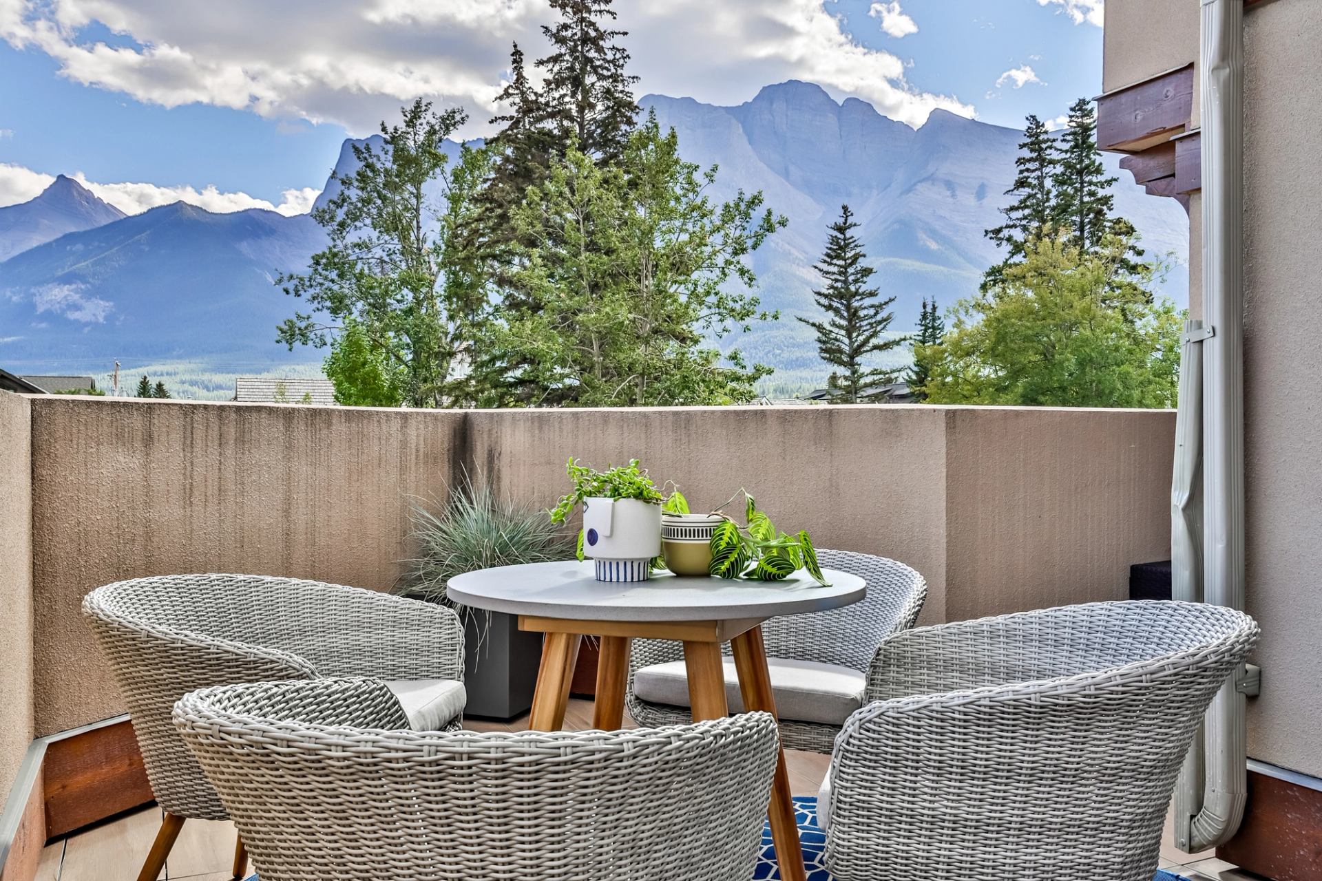 Outdoor patio with a table and chairs, overlooking majestic mountains and trees.