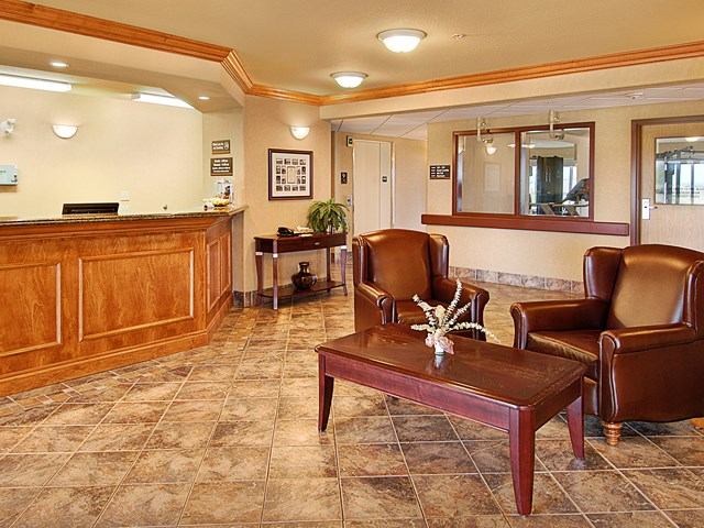 Lobby at Canalta Provost with reception desk, leather chairs, coffee table, and tiled floor.