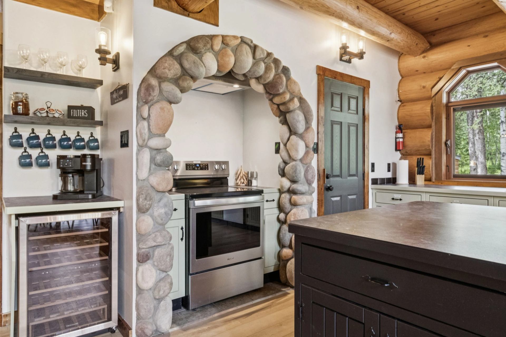 Rustic kitchen with stone arch, log walls, and modern appliances.