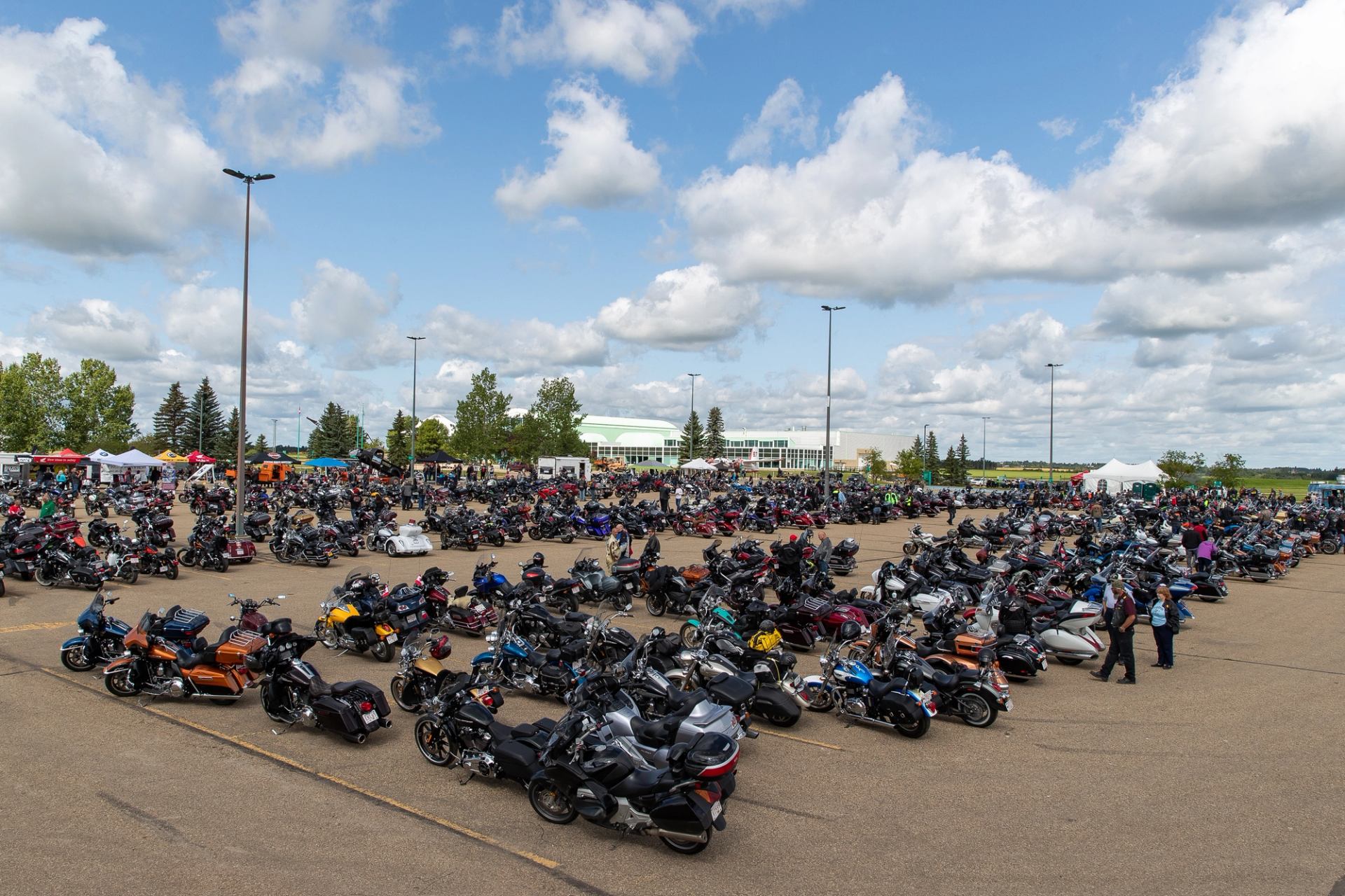 Wide view of a large parking lot filled with hundreds of parked motorcycles.