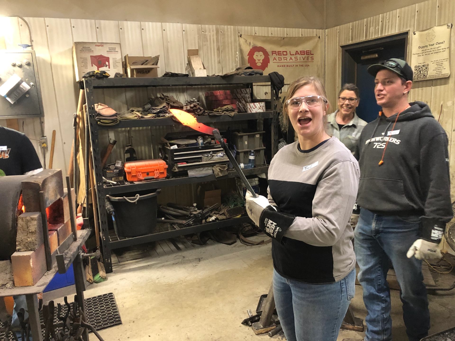 Participants heating and holding forged steel inside a knife making workshop.