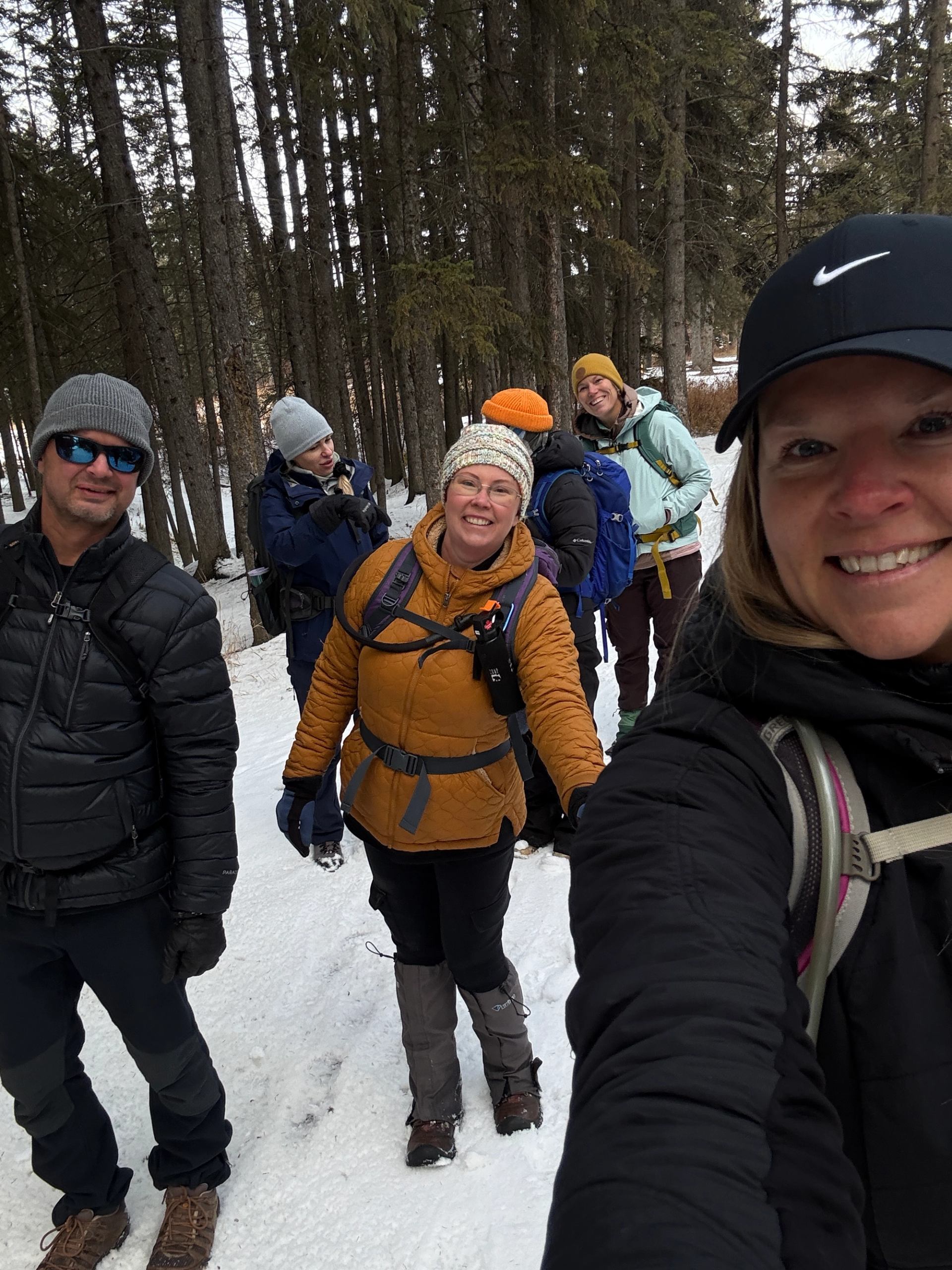 A group hiking on a snowy forest trail wearing winter clothing.