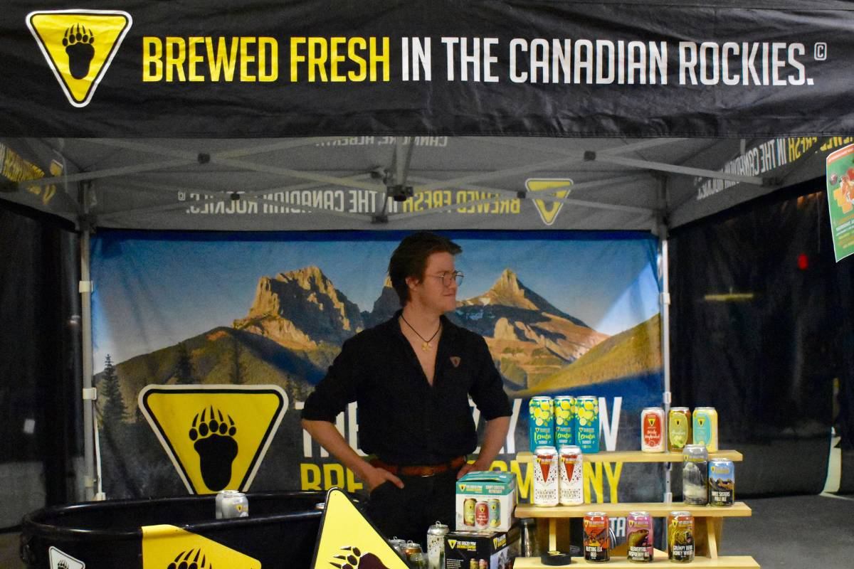 Craft beverage booth with canned drinks and merchandise displayed under a banner reading “Brewed Fresh in the Canadian Rockies.”