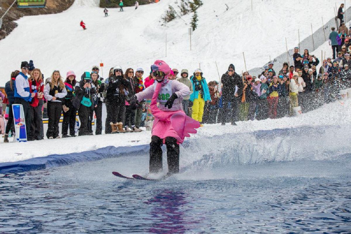 Costumed skier gliding across a water pool during the Slush Cup event at Banff Sunshine Village.