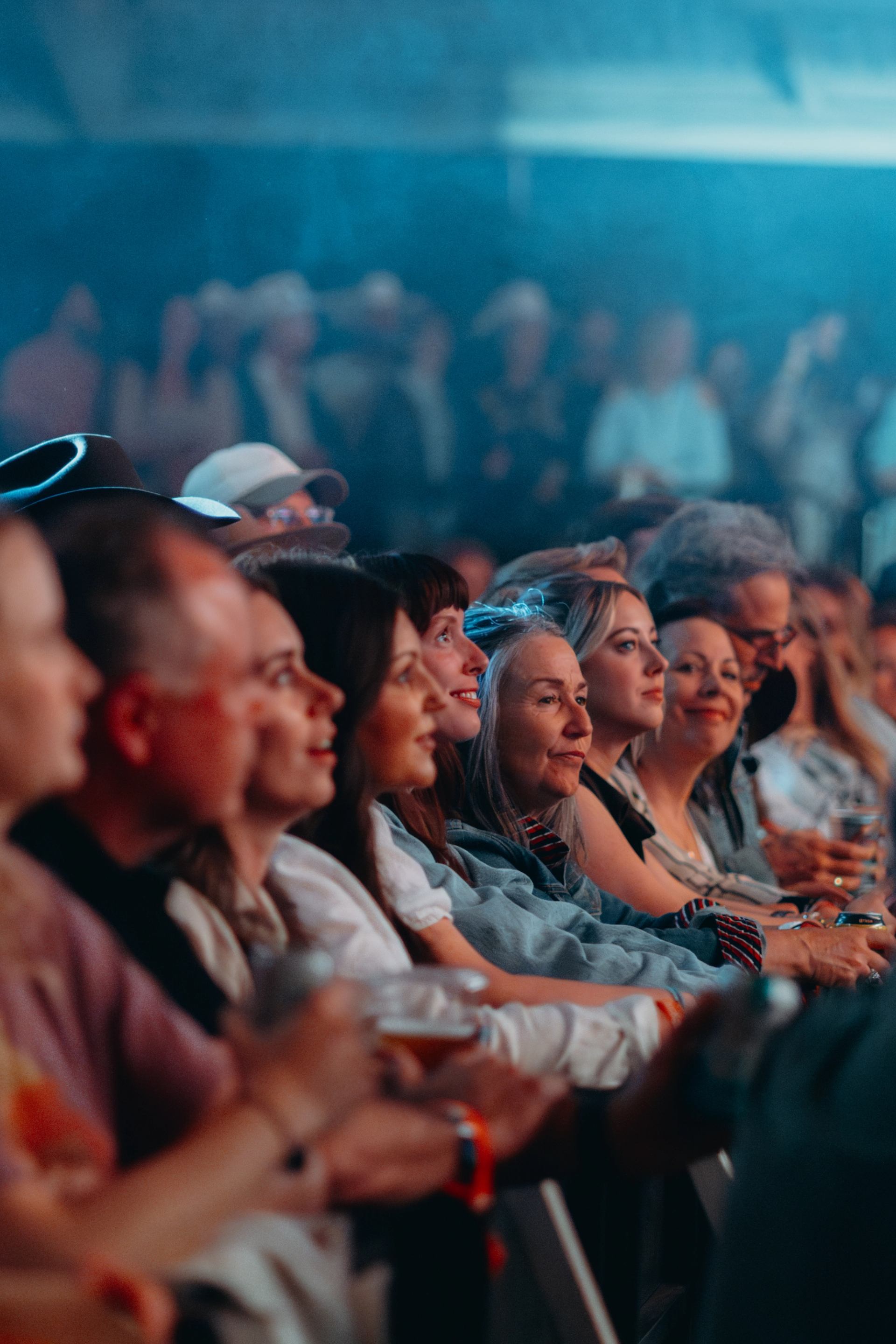 Audience members sit in rows at an indoor event, facing the unseen stage.