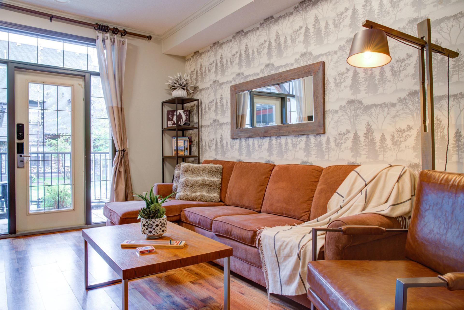Cozy living room with leather sofa, patterned wall, and warm natural light.