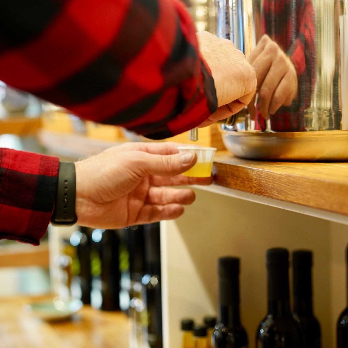 erson in plaid shirt pouring liquid sample from metal container.