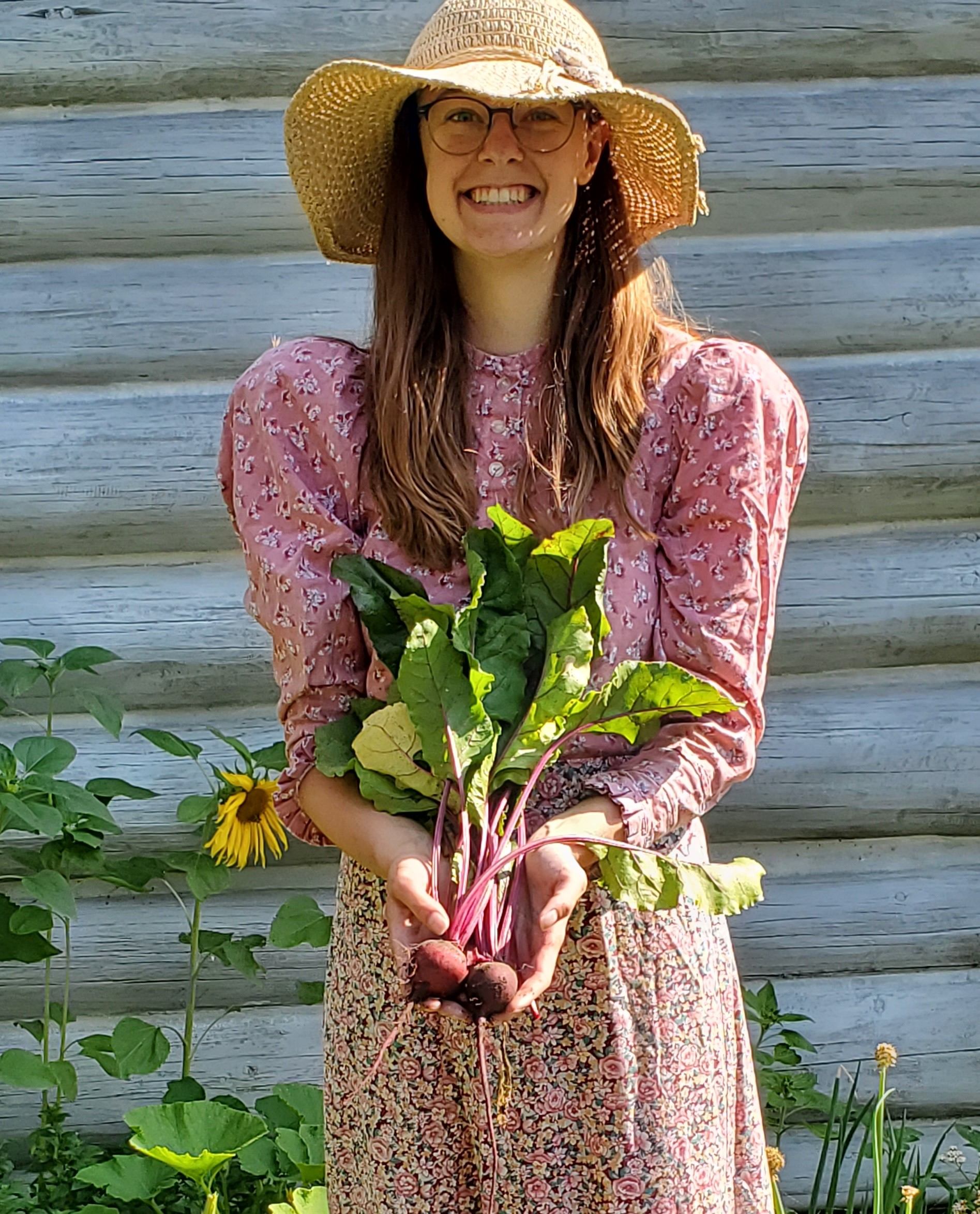 An Interpreter dressed in a historical outfit holds a handful of beets for the camera.