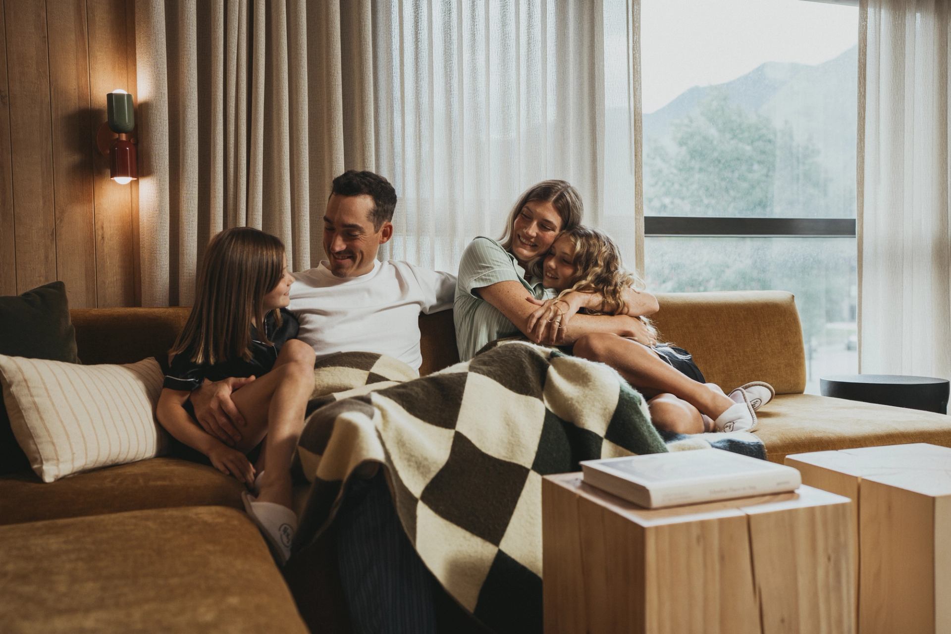 Family of four cuddled and hugging on a couch in a family suite.