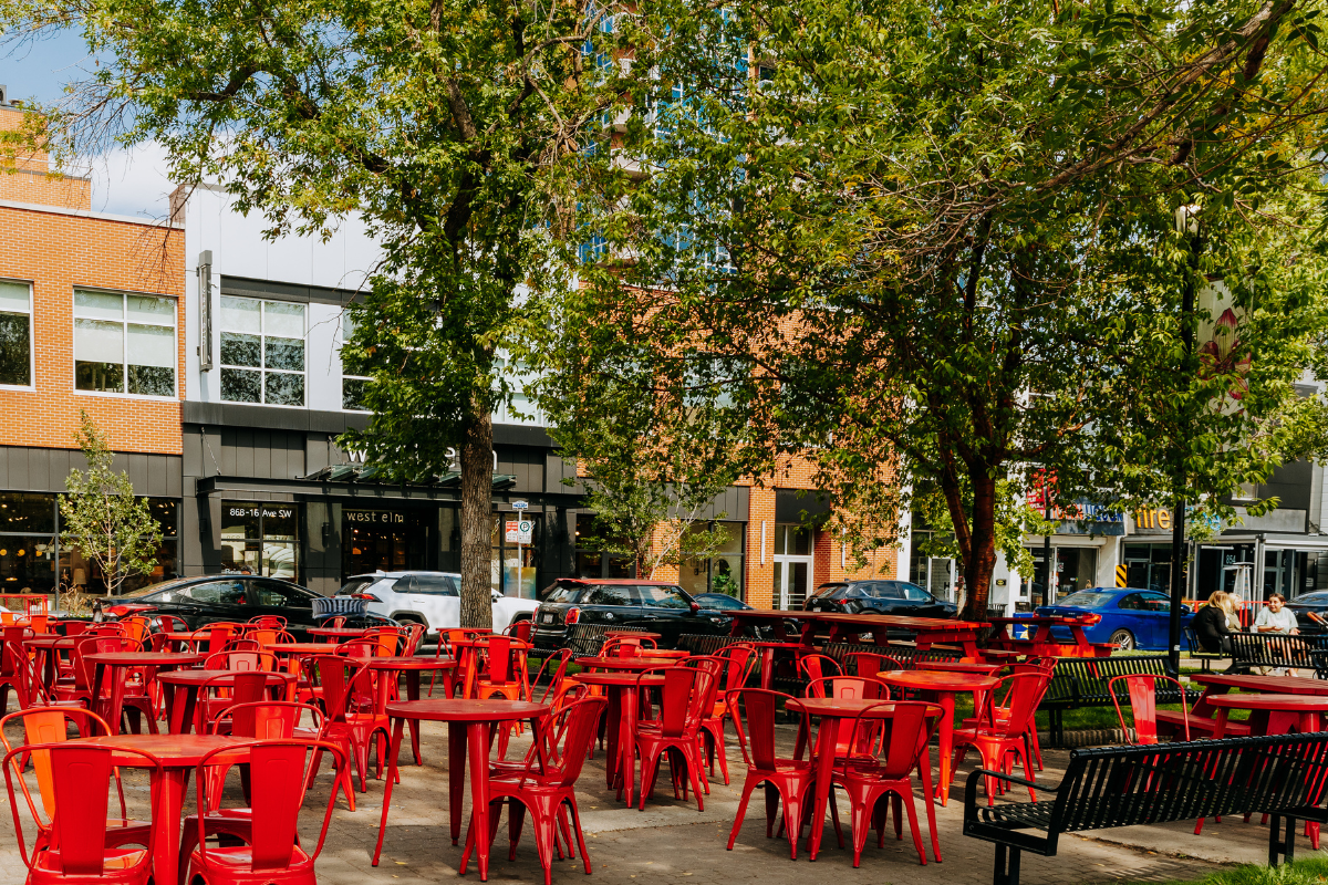 Red tables and chairs beneath trees.