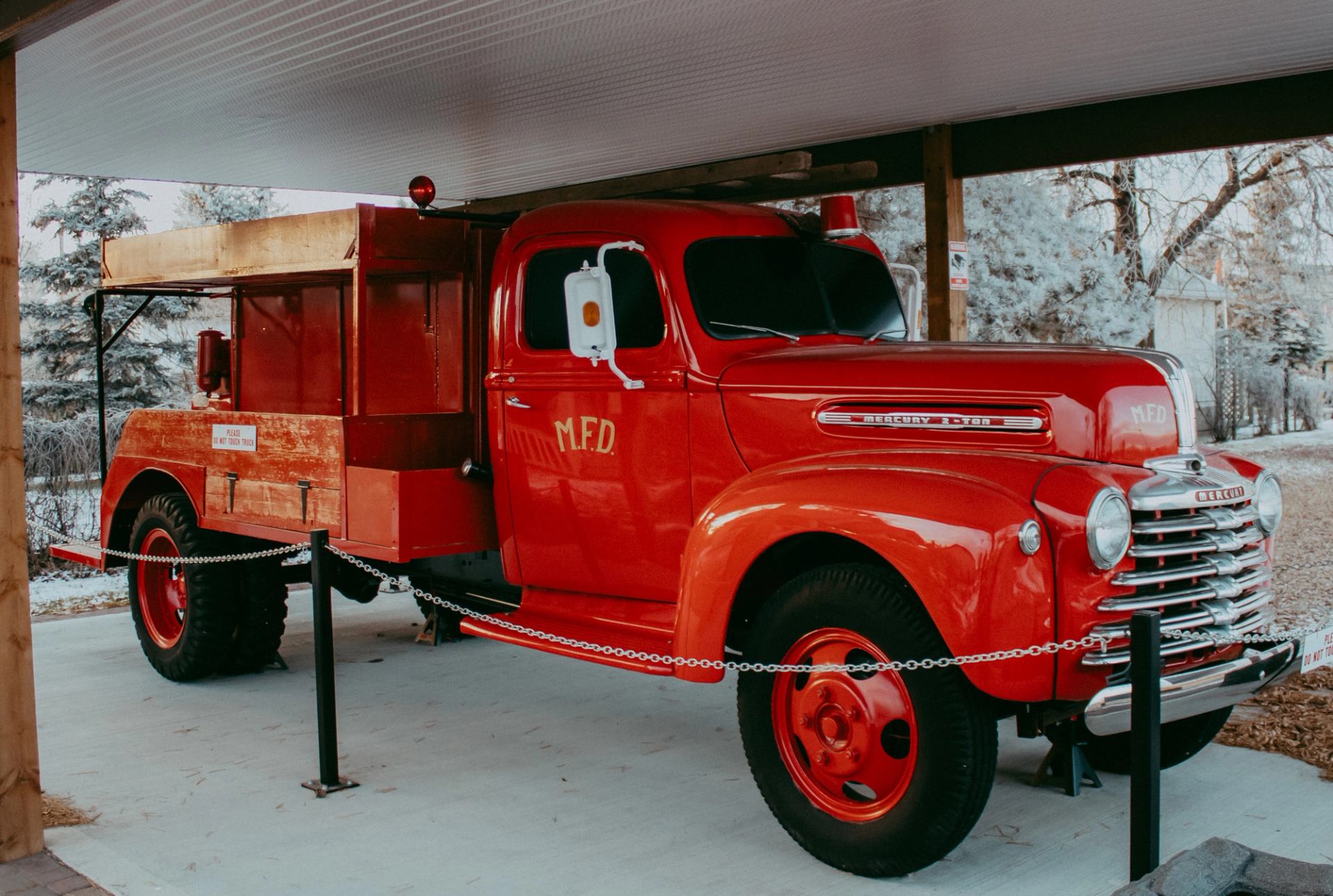 Vintage red fire truck displayed under a covered structure at Millet Museum.