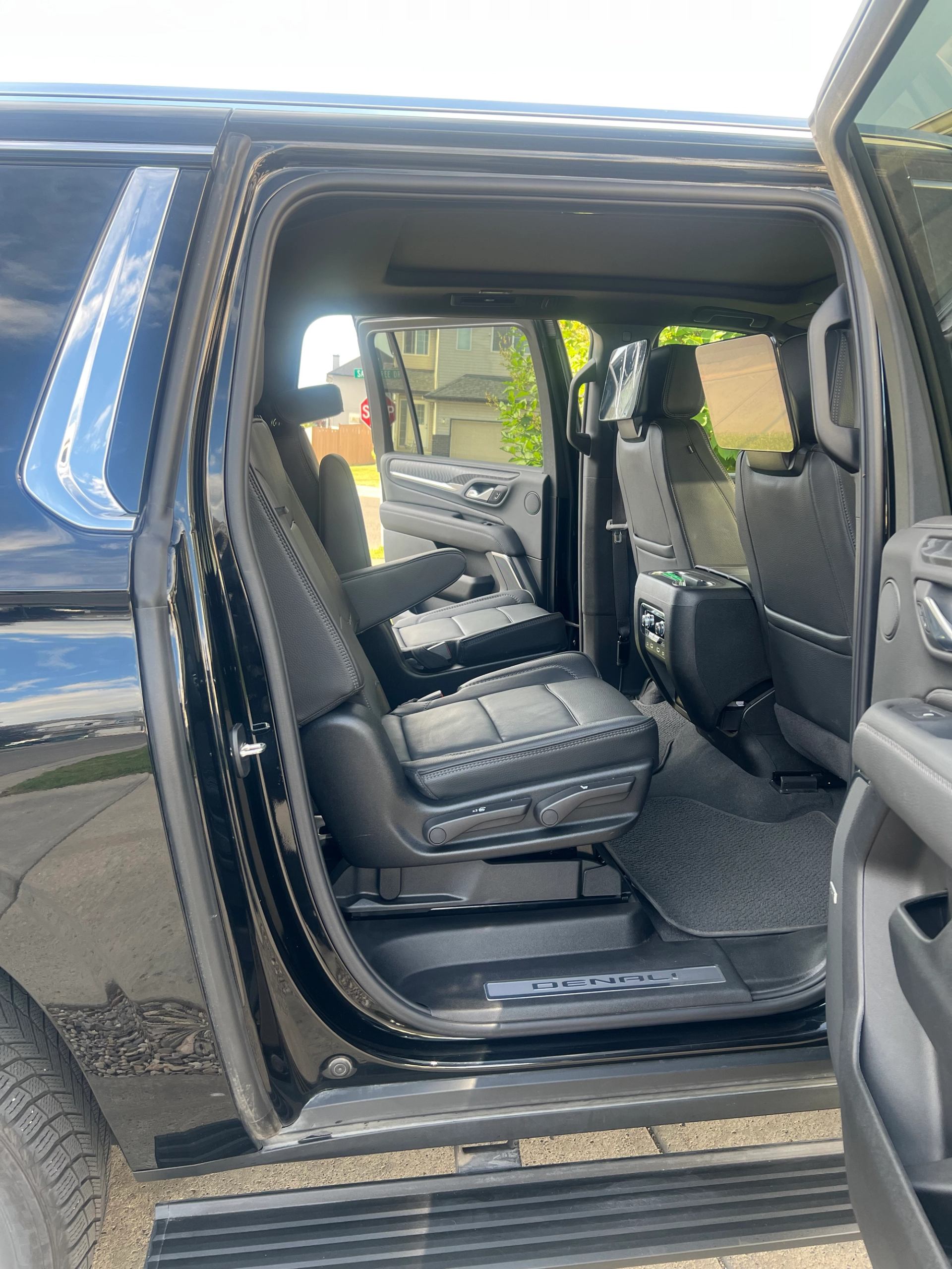 Open rear door of black Denali SUV showing leather seats and rear entertainment screens.