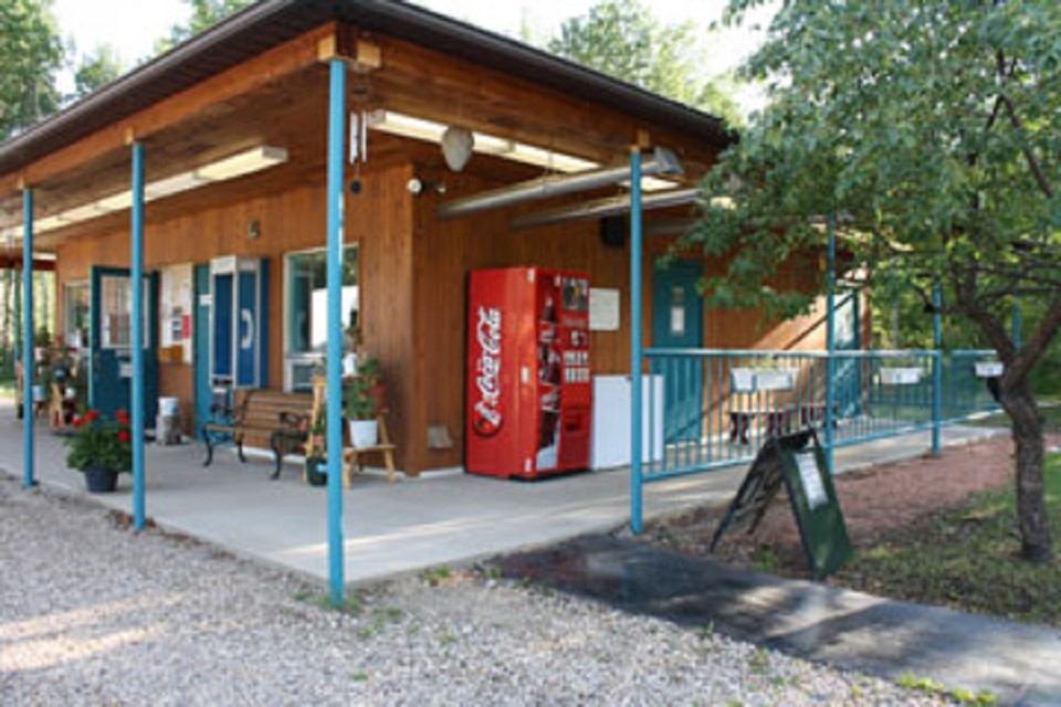 Teal-trimmed building at Sherk’s RV Park with vending machine, benches, and walkway.
