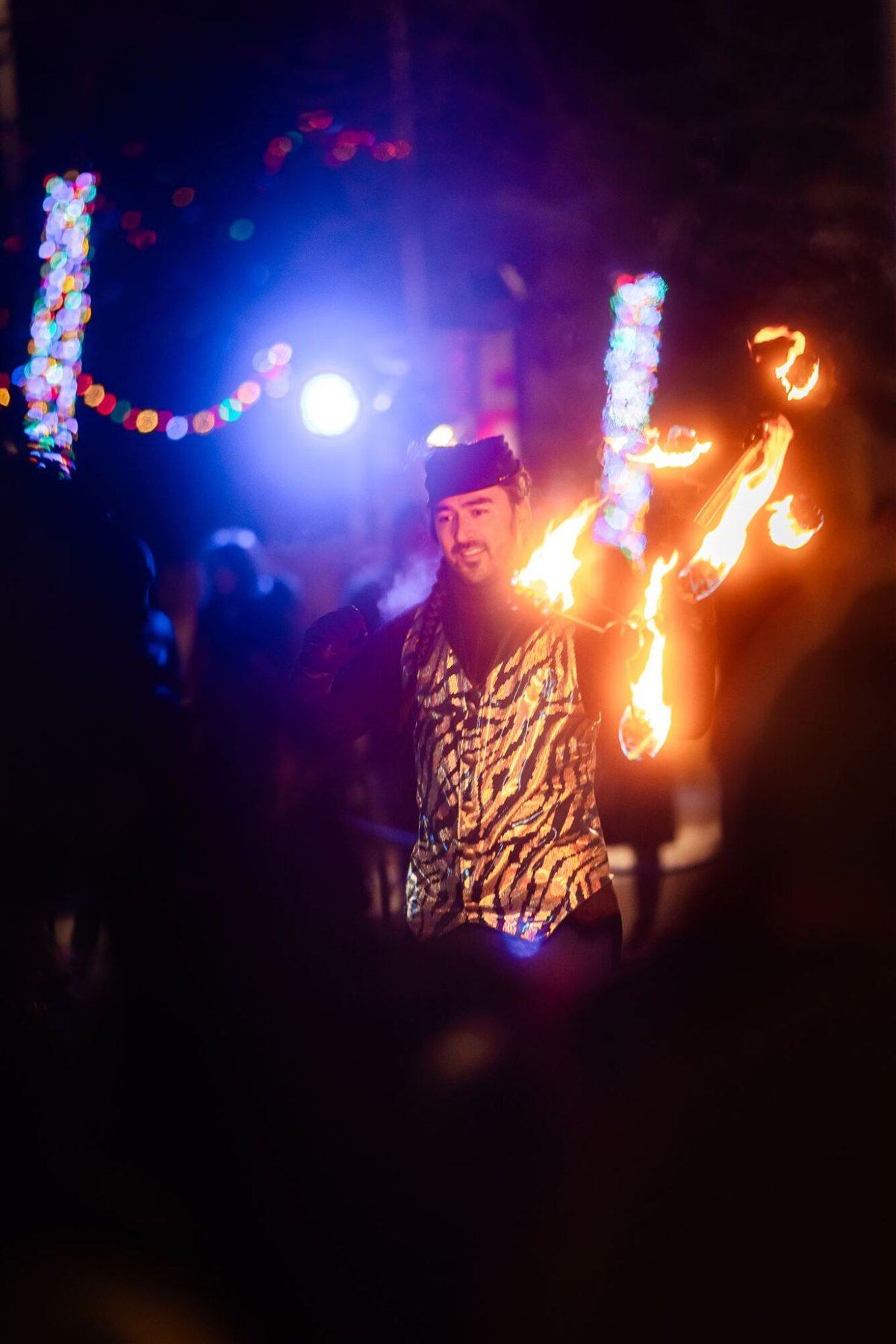 Performer spinning flaming sticks during outdoor night festival