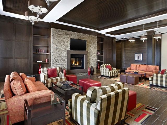Modern lobby with fireplace, striped chairs, and orange sofas at Four Points By Sheraton.