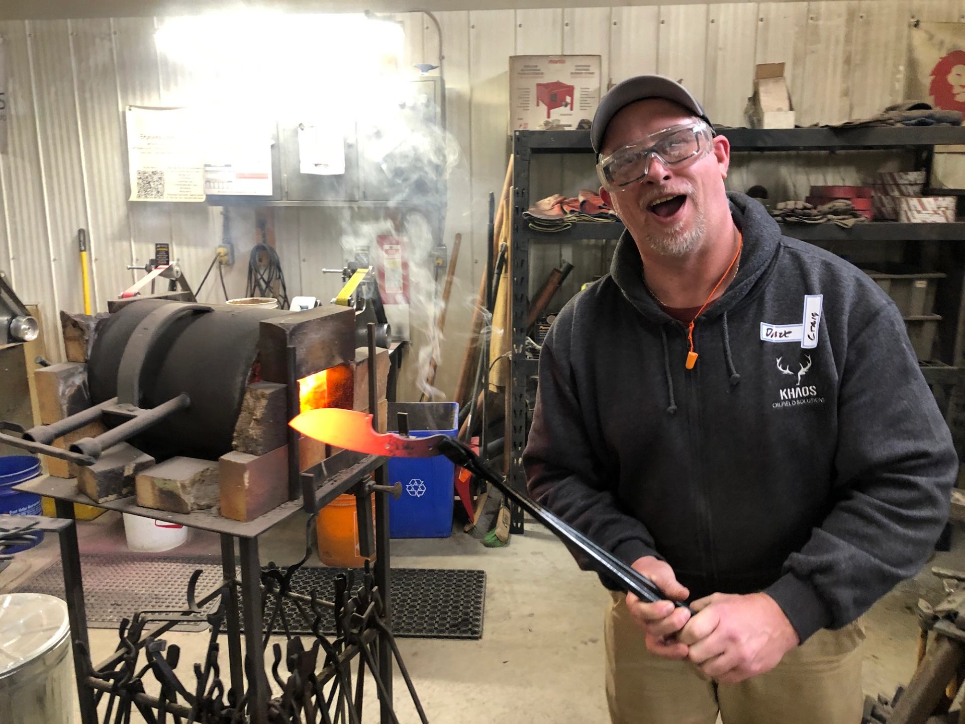 Person holding heated steel beside a forge during a knife making class.