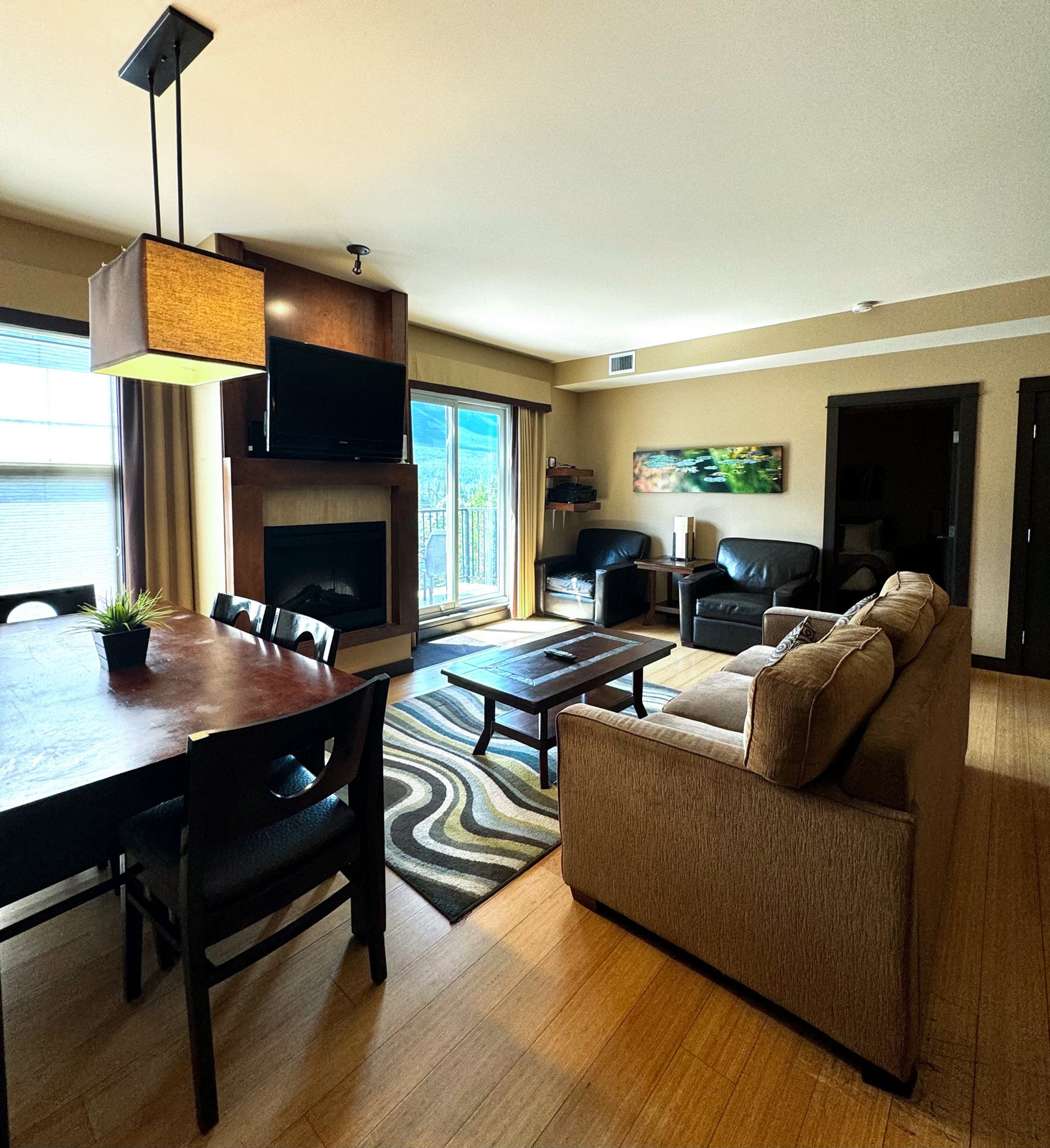 Stylish lodge living room with fireplace, dining area, and balcony access.