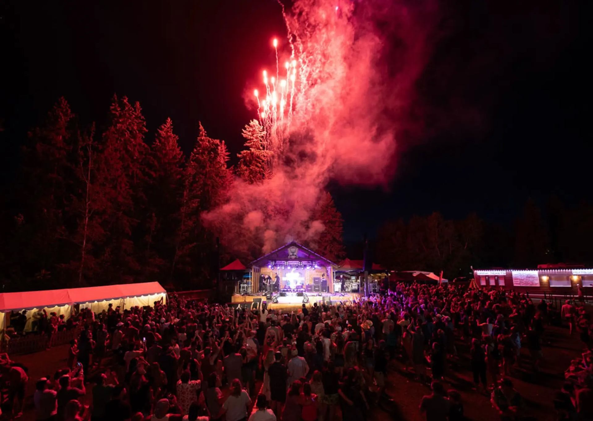 A fireworks show behind the stage with concert goers watching.