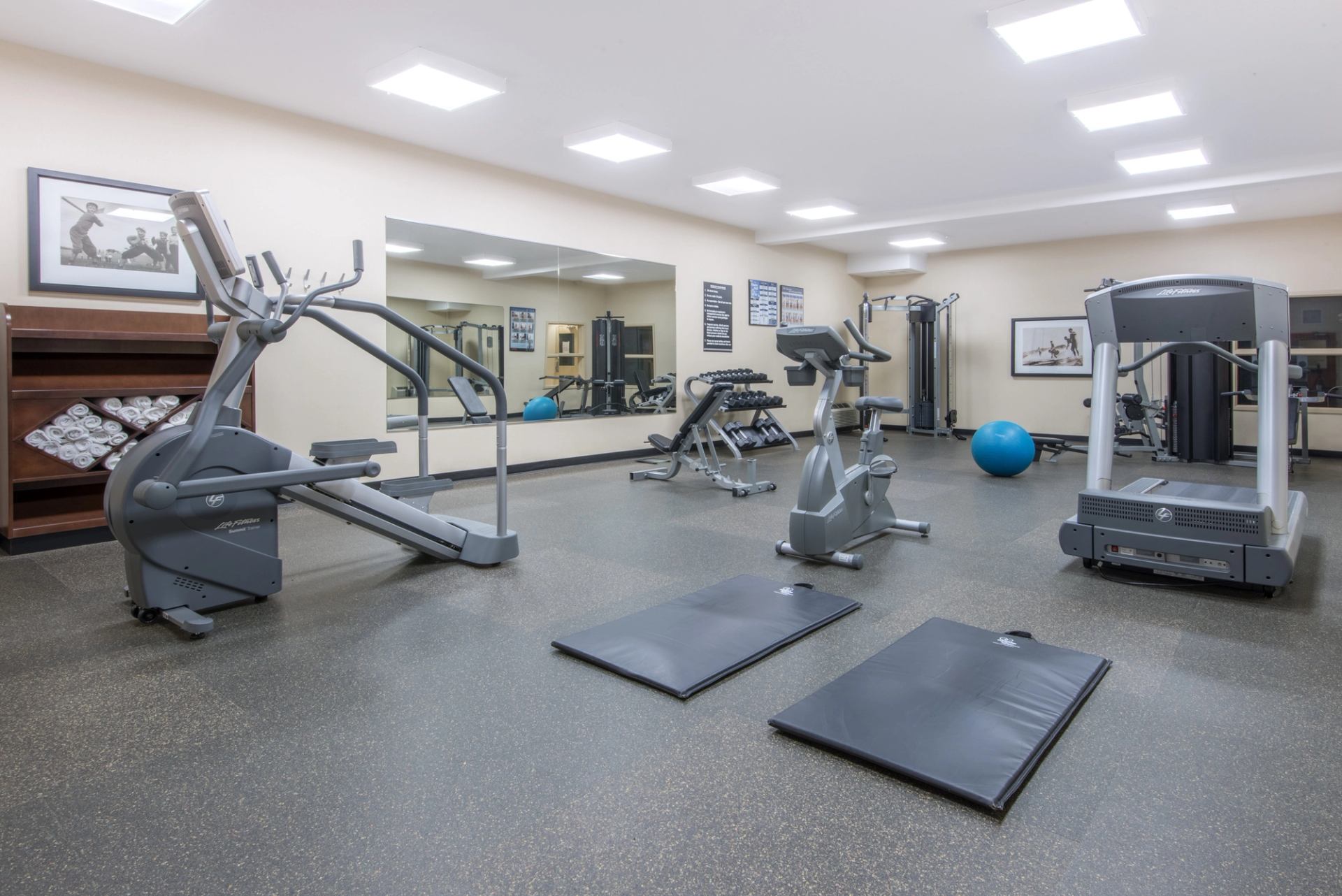 Hotel fitness room with cardio machines, weight benches, dumbbells, mats and exercise ball.