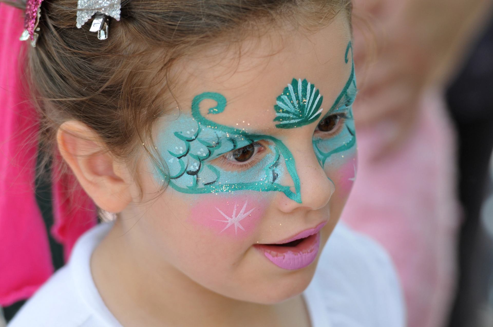 Close view of a child’s hair with sparkly bow clips and bright outdoor light.