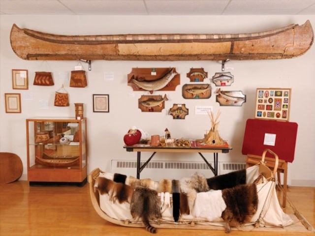 Museum exhibit with canoes, pelts, baskets, and Indigenous cultural artifacts.