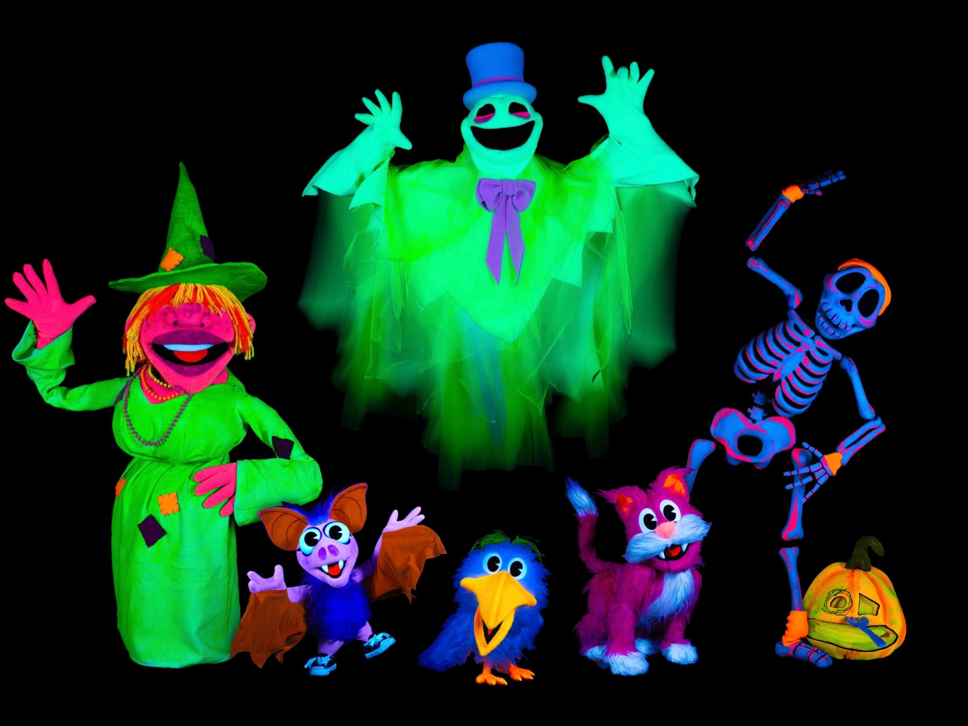Neon puppets of witch, ghost, skeleton, bat, bird, cat and pumpkin on black background.